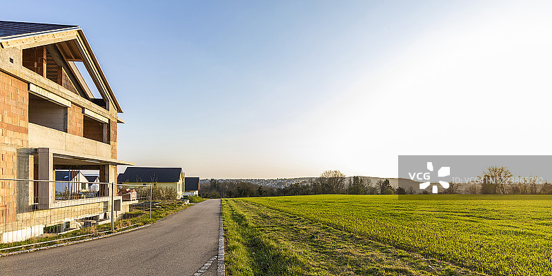 德国，巴登-符腾堡，威布林根，田野和乡村公路前的现代房屋正在建设图片素材