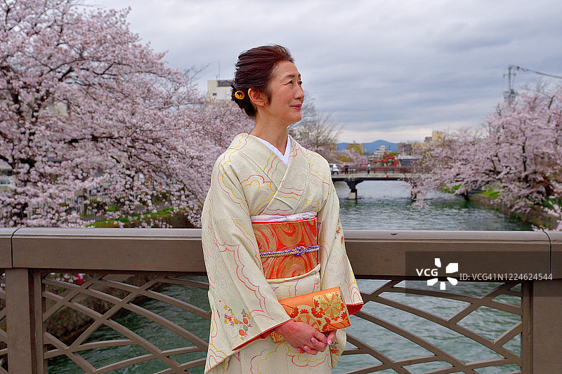 穿着和服的日本妇女在京都冈崎运河周围欣赏樱花图片素材