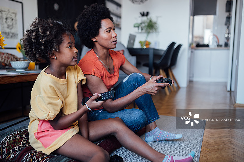 母亲和女儿一起玩电子游戏的侧视图图片素材