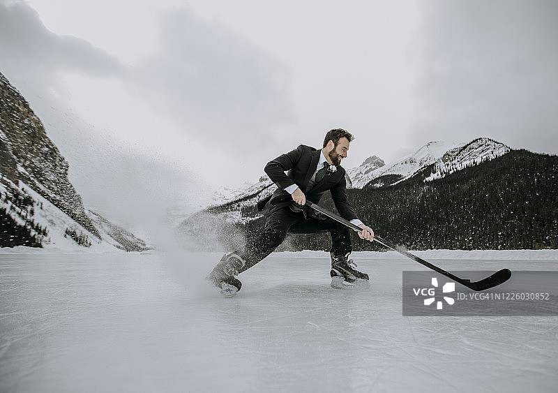 冰球运动员在结冰的湖面上穿着西装迅速停下并向冰面喷射图片素材