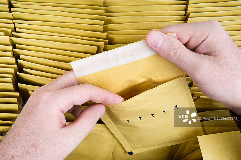 检查新一批黄色气泡信封。装满航运邮件的盒子。图片素材