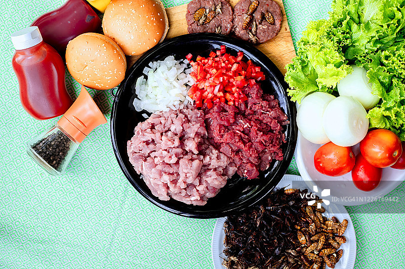 自制汉堡配牛肉或猪肉，昆虫配生菜和奶酪，蔬菜，酱汁，放在桌上图片素材
