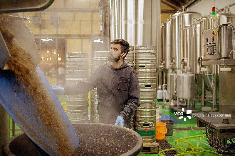 酿酒人站在油罐旁卸载用过的啤酒花图片素材