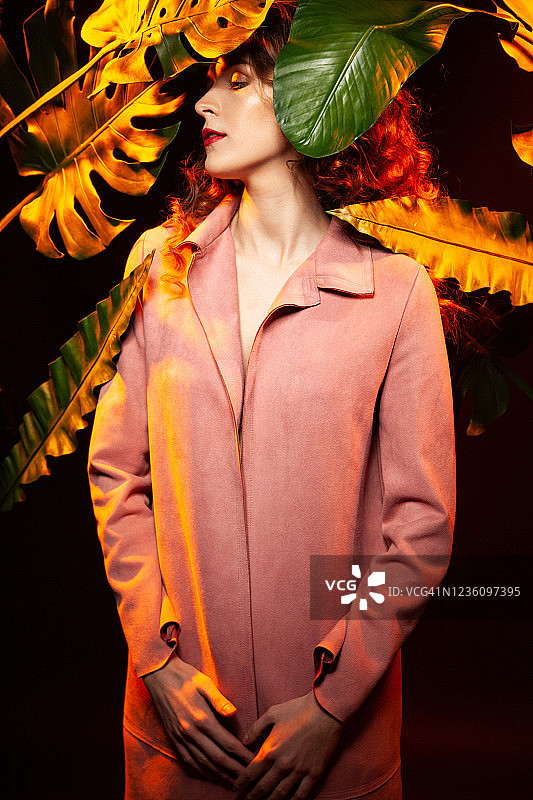 性感的女性模特对着五颜六色的植物叶子图片素材