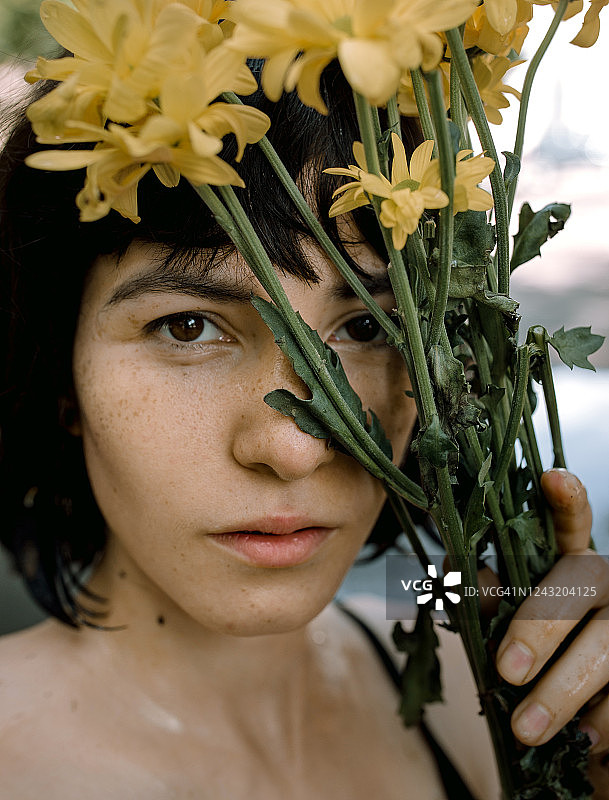 一个年轻女子与黄花的特写肖像图片素材