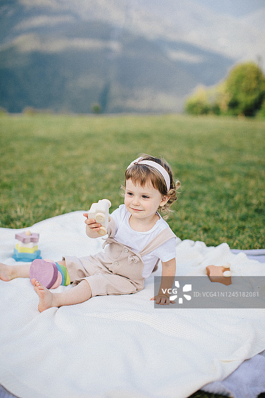 可爱的小女孩在山上的草地上玩彩色的木制玩具图片素材