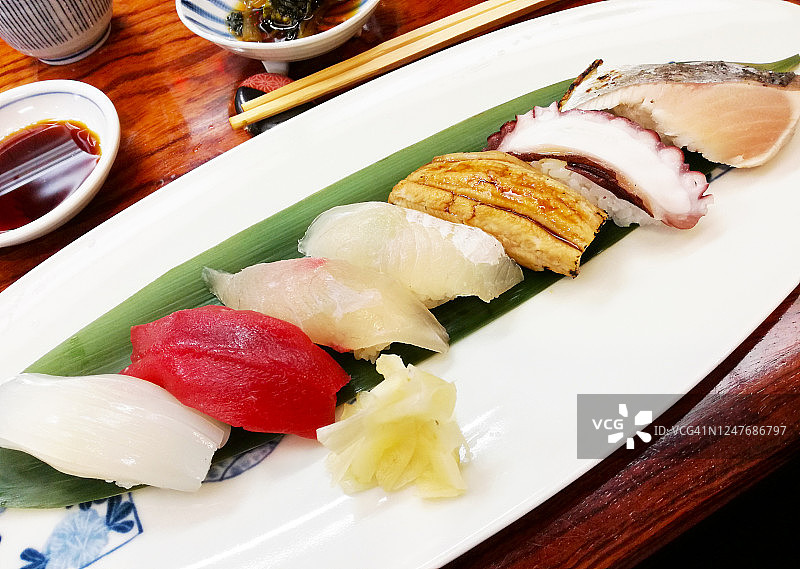手握寿司盘与鱿鱼，金枪鱼，海鲷，比目鱼，康格鳗鱼，章鱼，鲣鱼，在餐厅供应图片素材