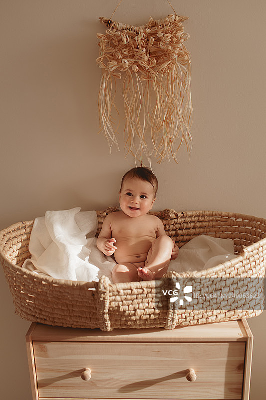 微笑的婴儿坐在摩西篮子里。
6个月大的婴儿坐在树麻花编织的篮子摇篮里。婴儿eco托儿所。图片素材