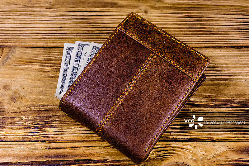棕色皮革钱包和一百元钞票上的木制背景图片素材