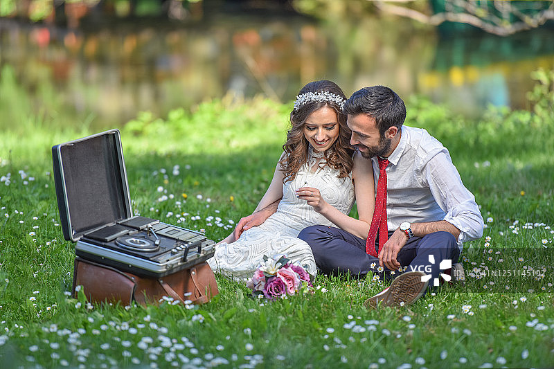 年轻的夫妇在美丽的河流背景的草地上有浪漫的爱情图片素材