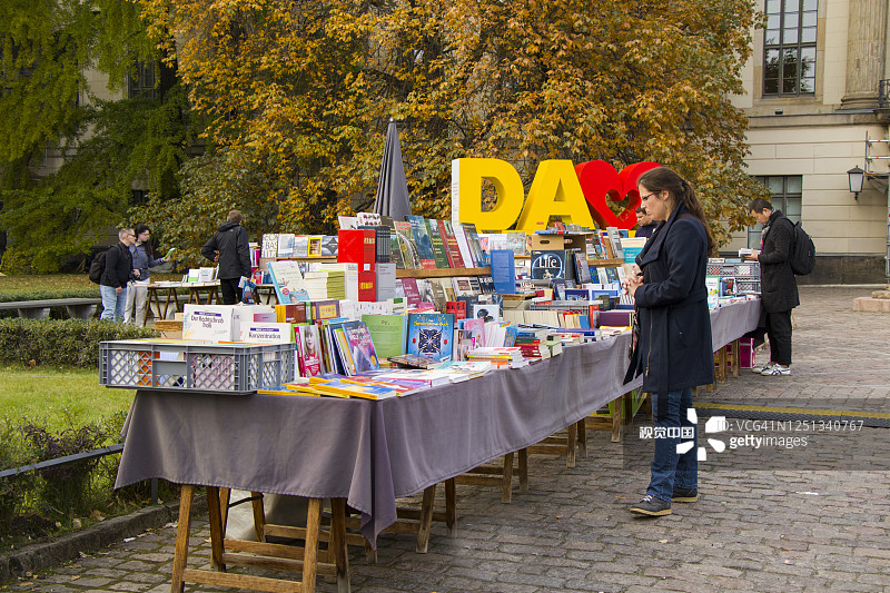 柏林中心的跳蚤市场。书出售。年轻女子bay books。图片素材