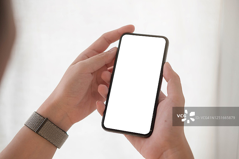 女人手里拿着白屏幕的智能手机图片素材