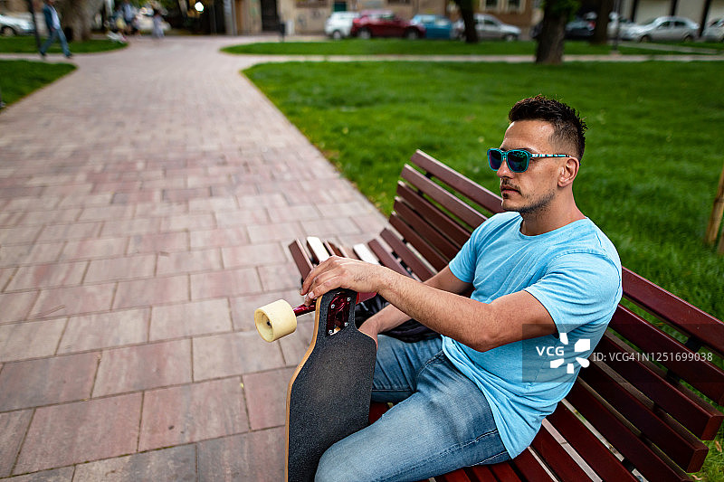 带长板坐在公园长椅上的男子图片素材