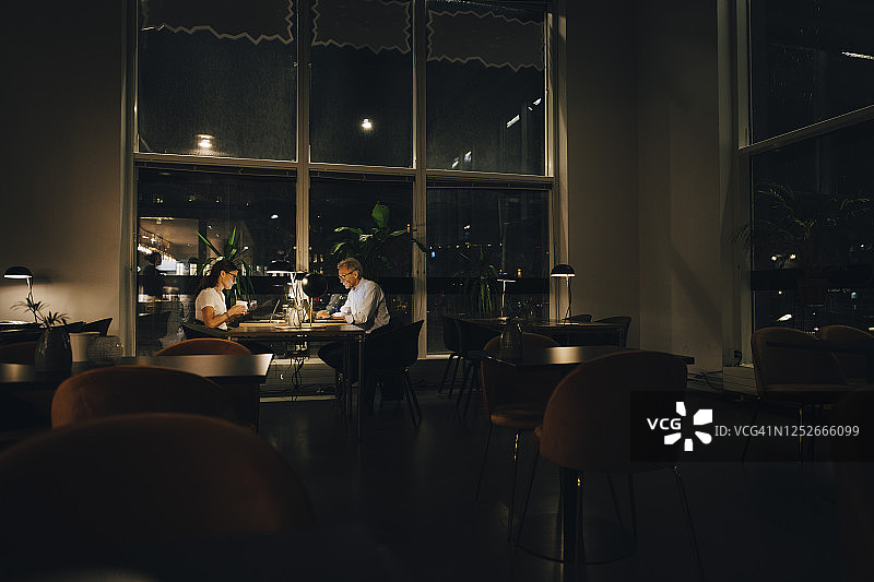 男性和女性企业家晚上在黑暗的办公室工作到很晚图片素材