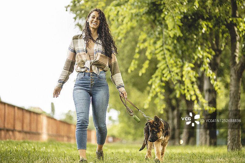 一个年轻女子和她的德国牧羊犬在公园散步图片素材