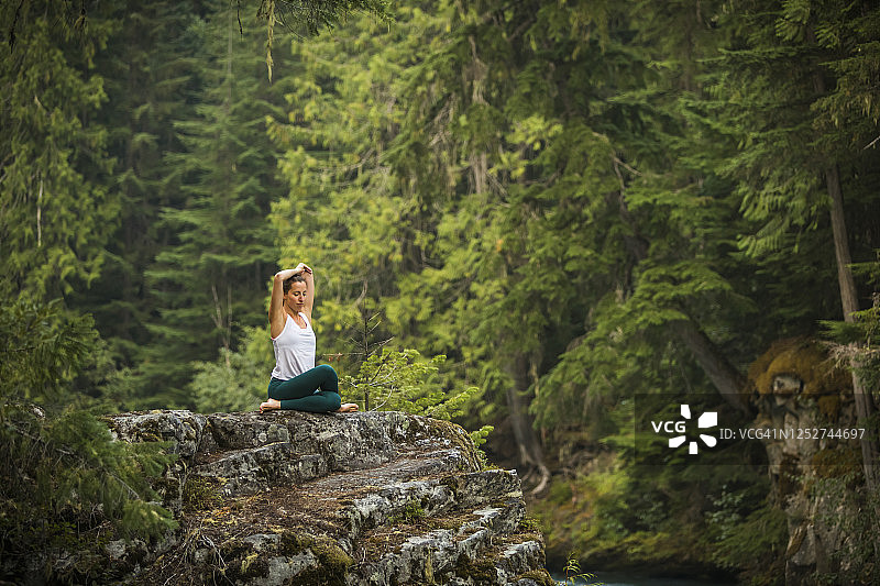 年轻女子练习瑜伽和冥想在森林设置。图片素材