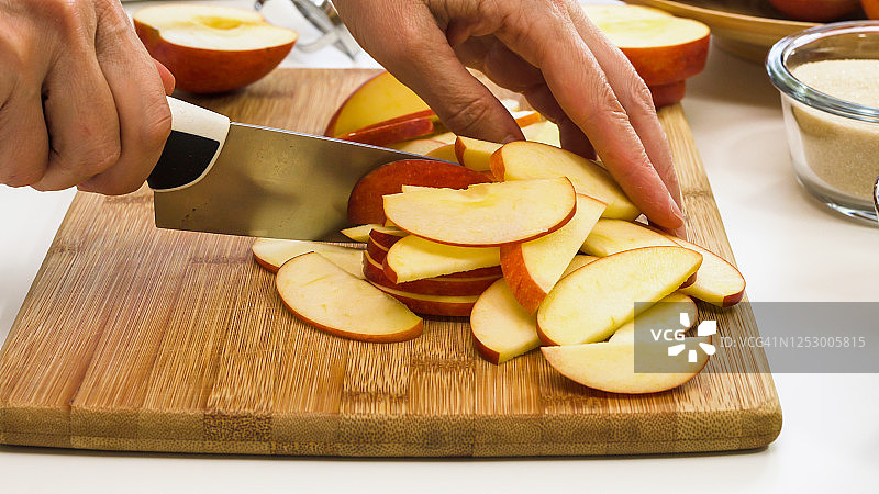 一个女人在切苹果，在白色背景的木头砧板上图片素材