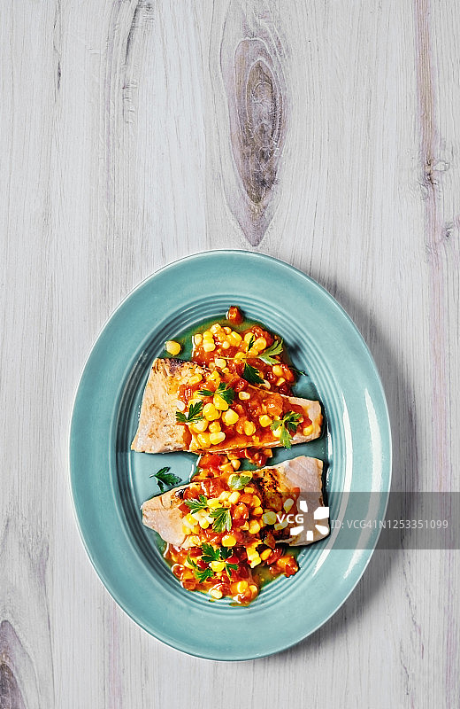 一盘烤鲑鱼和玉米在木背景图片素材