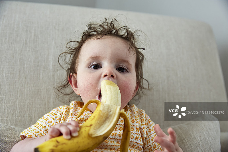 一个婴儿坐在椅子上吃香蕉图片素材