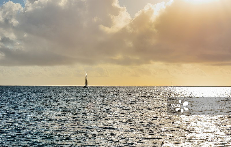 夕阳下金色海面上的帆船图片素材