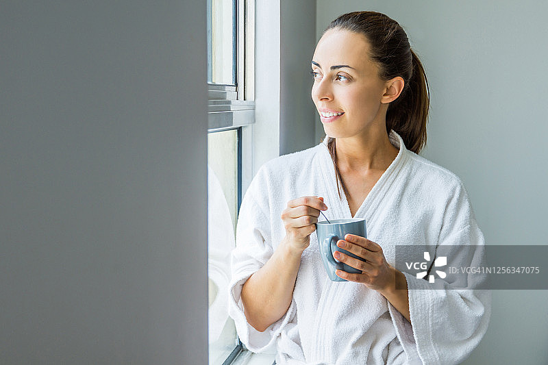 一个女人在早上喝着咖啡，看着窗外图片素材