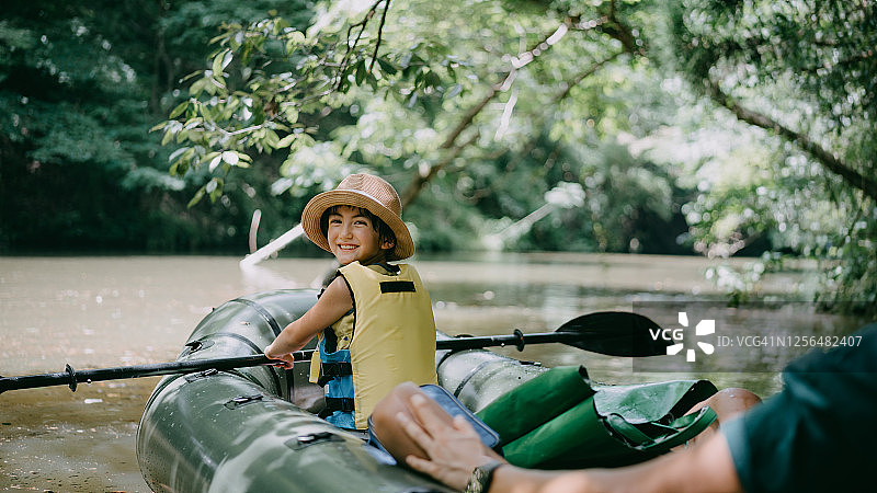快乐的女孩在森林里划船穿过河流图片素材