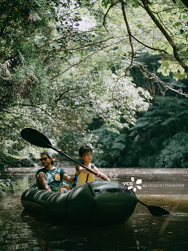 年幼的孩子和父亲在森林里划船过河图片素材