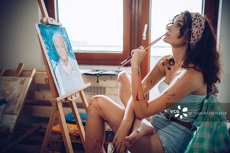美丽的年轻女艺术家在她的艺术工作室绘画图片素材