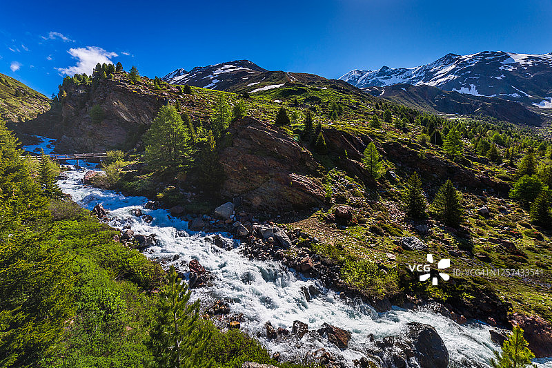 瀑布流入斯特尔维奥国家公园的雪山山谷，弗尼-瓦尔富尔瓦，意大利阿尔卑斯山图片素材