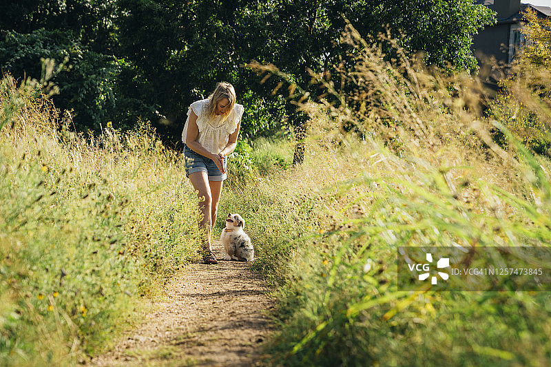 一个女人在公园里和她的迷你澳大利亚牧羊犬聊天图片素材