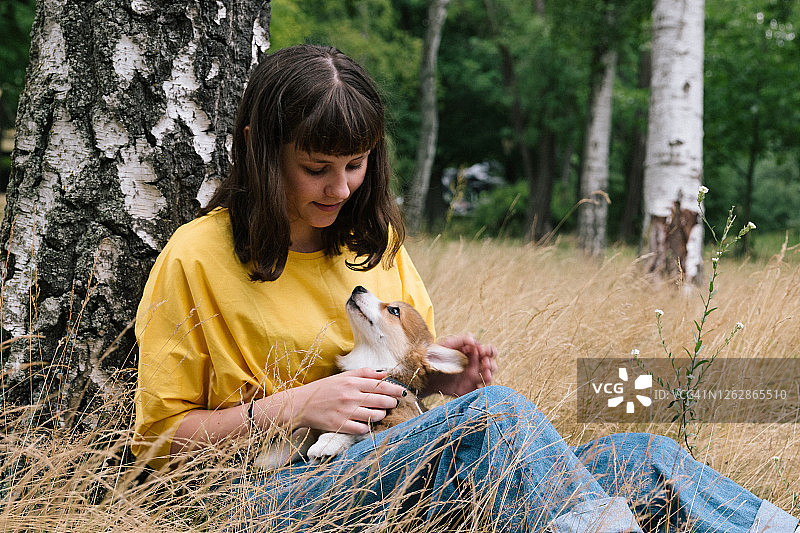 可爱的少女抱着一只柯基小狗，自然背景图片素材