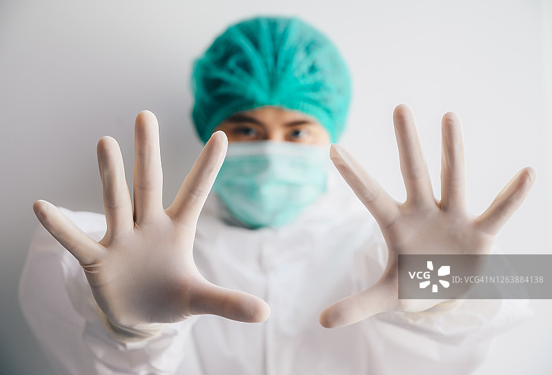医护人员戴上口罩和防护服，用手势示意以保持社交距离。图片素材