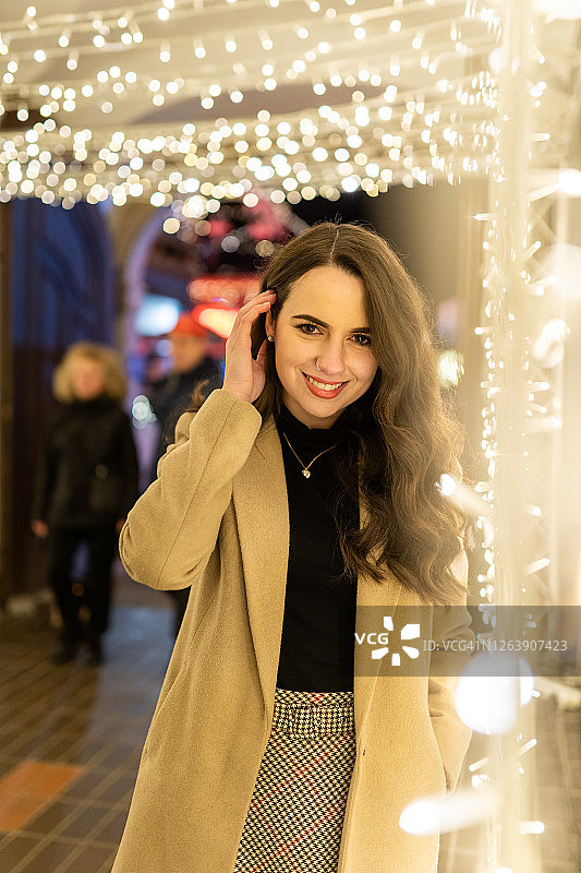 年轻女子站在圣诞彩灯中图片素材