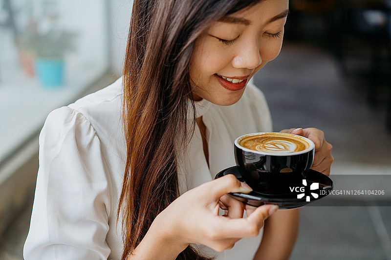年轻的亚洲女人拿着杯咖啡碟图片素材
