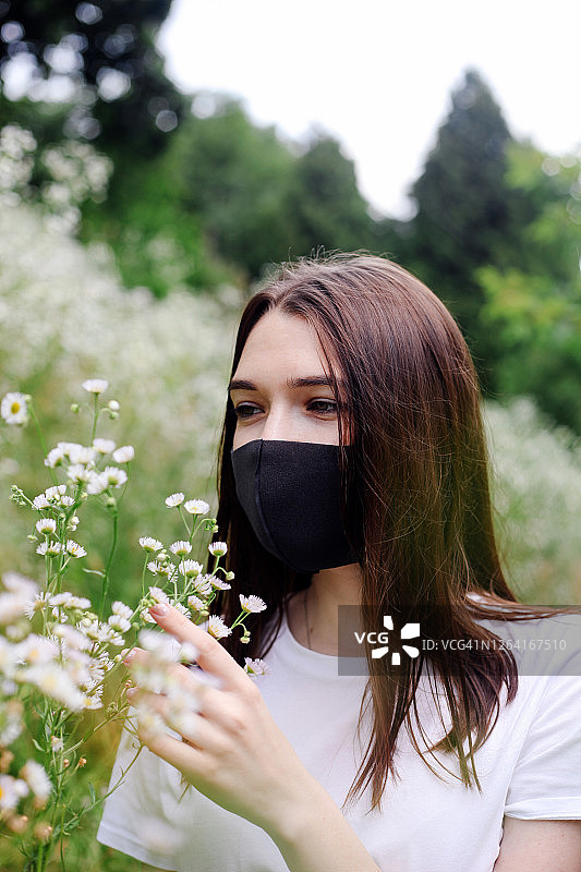 街头夏日画像的年轻女子戴着防护面具。covid-19概念、冠状病毒大流行与隔离。图片素材