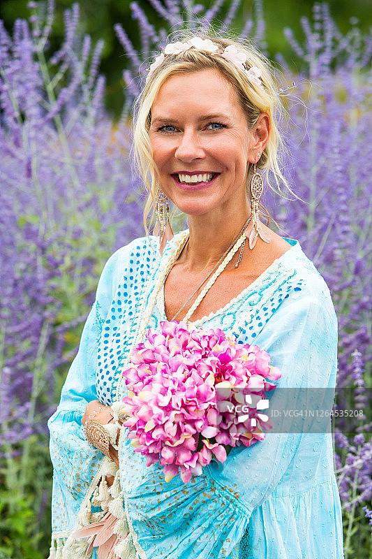 40多岁的金发女人站在紫色的花丛中的肖像图片素材