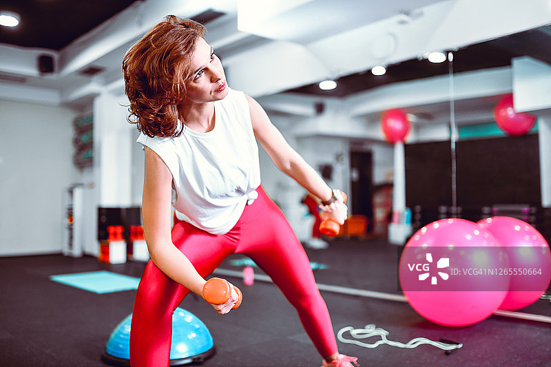 运动女性在健身房用哑铃锻炼图片素材