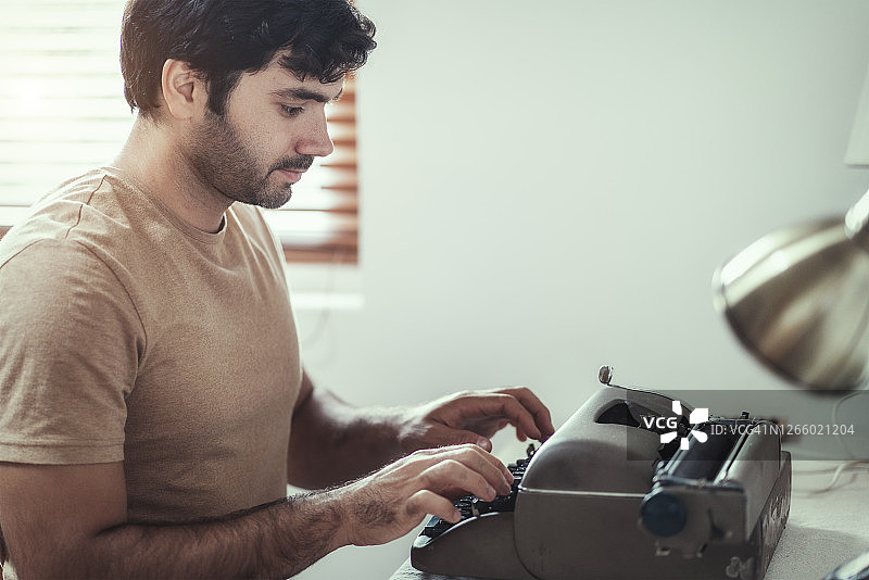 男子自信地在老式打字机上打字。图片素材