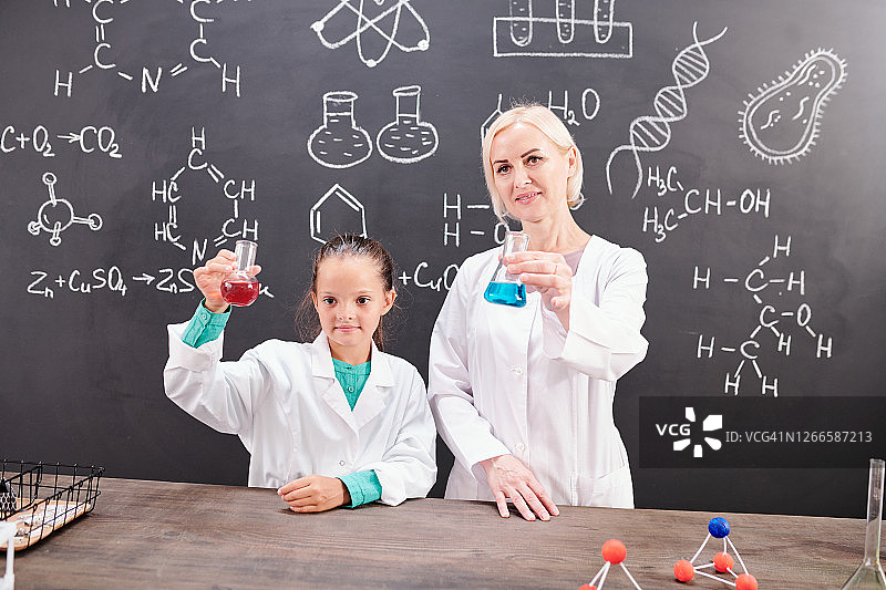 女学生，成功的化学老师穿着白大褂，拿着管子图片素材