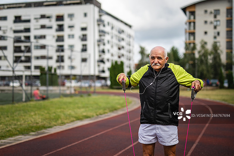 老人在城市的运动场上用皮带锻炼图片素材