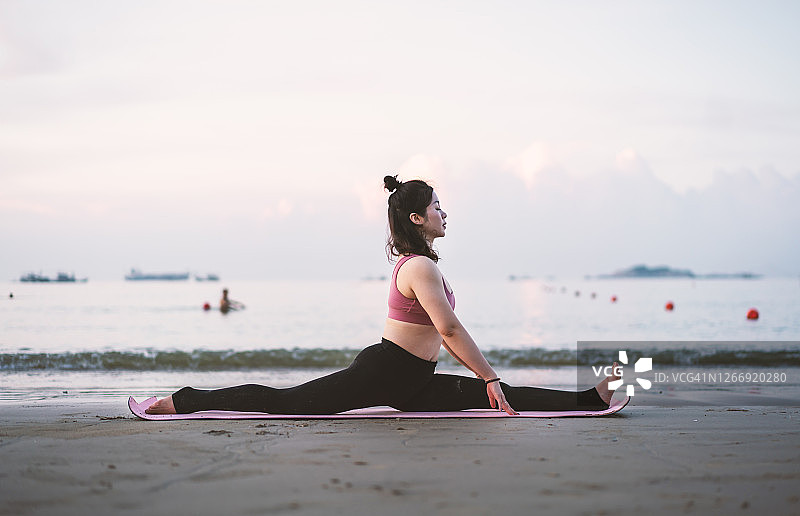 早上，一个亚洲女人在海滩上做瑜伽图片素材