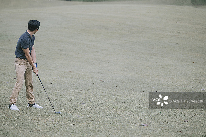 亚洲华人男子高尔夫球开球在马六甲雨中独自湿挥杆图片素材