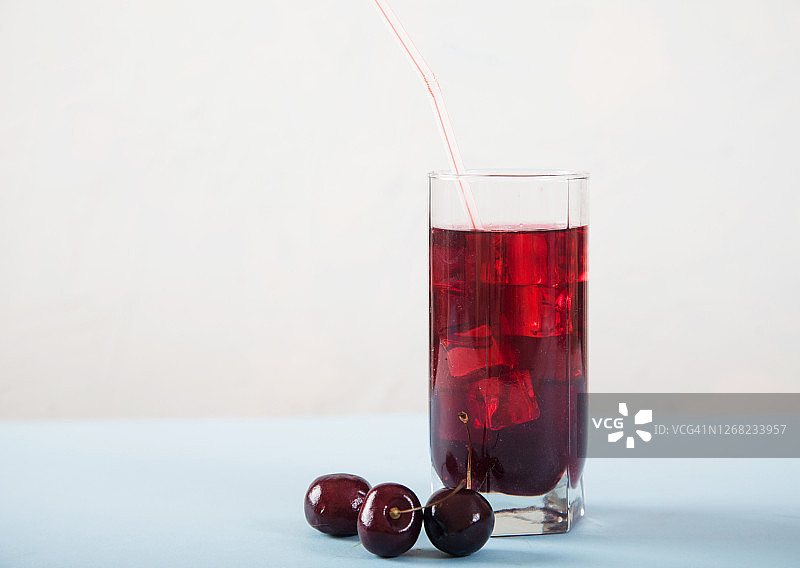 白桌子上放一杯加冰和樱桃的樱桃汁。复制spa。图片素材