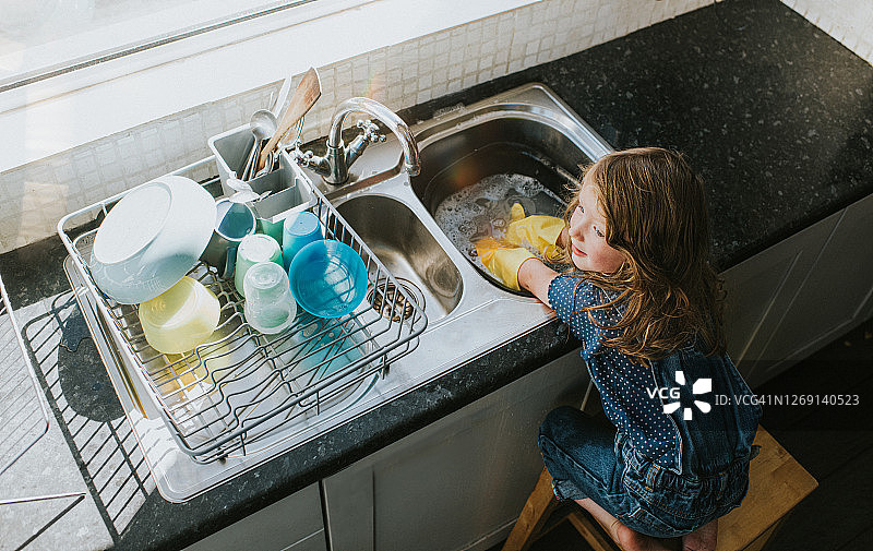 一个小女孩在水槽边洗碗图片素材
