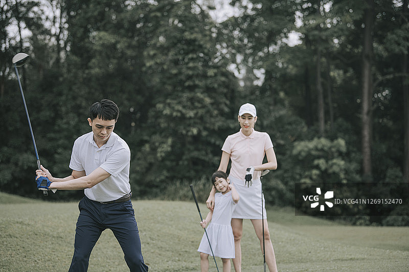 亚洲中国年轻夫妇高尔夫球开球和挥杆他的司机俱乐部在高尔夫球场图片素材