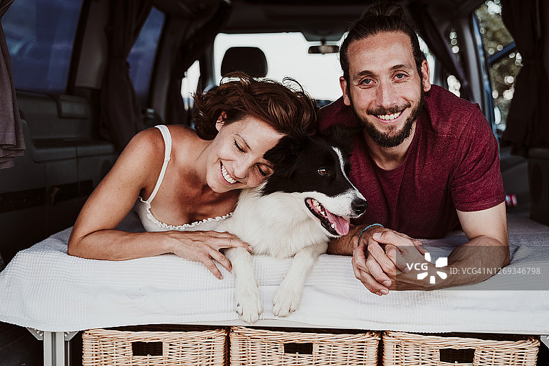 微笑的夫妇和狗躺在房车里图片素材