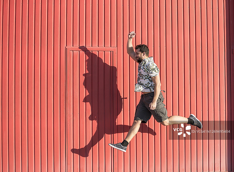 一个40岁的男人穿着快乐的夏装跳上红色的背景图片素材