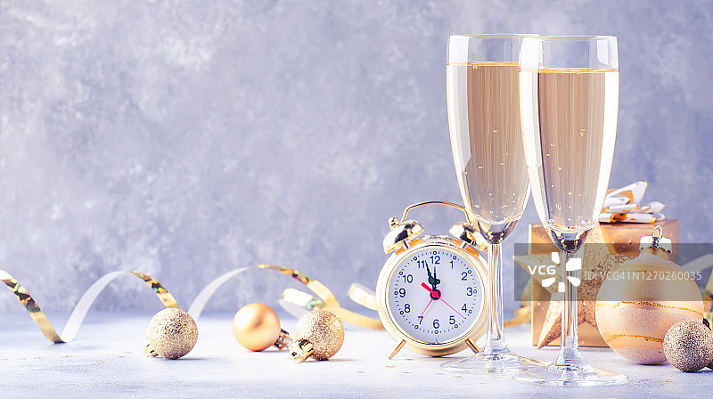 两个香槟杯和圣诞装饰在灰色金色的散景背景。庆祝新年快乐。选择性聚焦和小景深图片素材