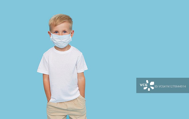 可爱的小男孩的肖像在保护面具在蓝色的背景。病毒防护和保健概念。图片素材