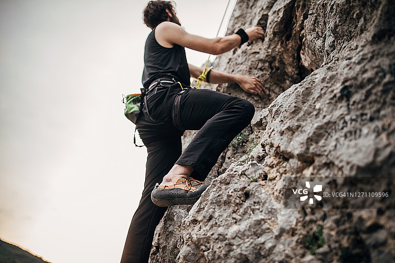 年轻的男性自由攀登者爬在岩石上图片素材